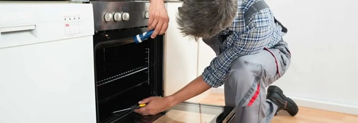 Oven repair technician inspecting and servicing an electric oven in Rochester, NY