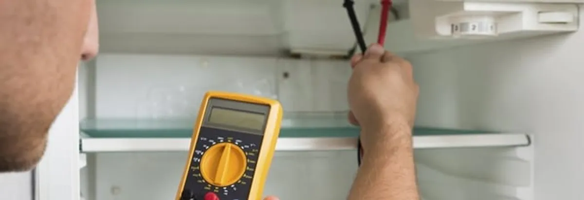 Refrigerator repair technician testing electrical components with a multimeter in Rochester, NY